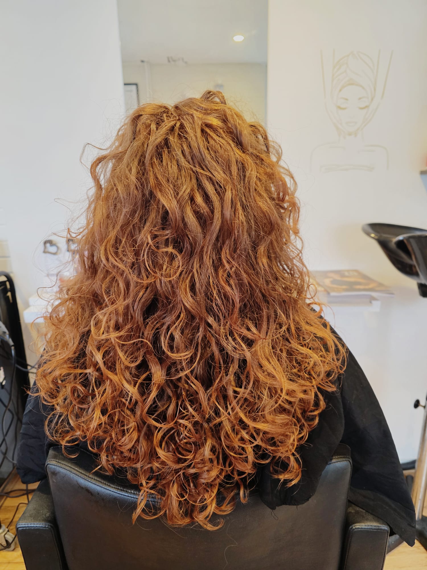 Lange koperkleurige krullen van achteren, in de salon